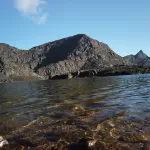 A clear mountain lake below rocky peaks on the Dagala trek