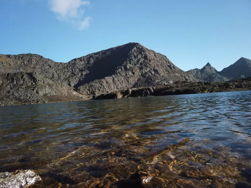 A clear mountain lake below rocky peaks on the Dagala trek