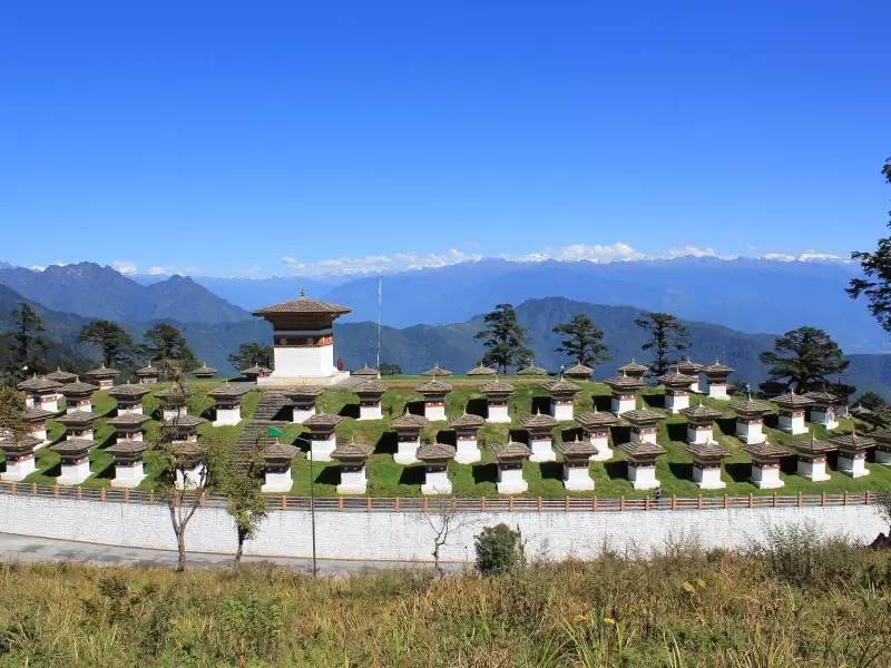 The 108 chortens on the Dochu La pass on a clear day, with the snow peaks of the Himalaya along the horizon