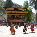 Black Hat dancers with drums in the festival ground at Paro Tshechu, watched by a large crowd