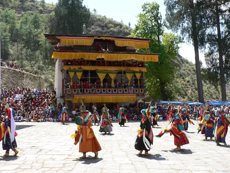 Black Hat dancers with drums in the festival ground at Paro Tshechu, watched by a large crowd