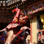 A masked dancer in a brocade robe during the dance of the Lord of Death at Paro Tshechu