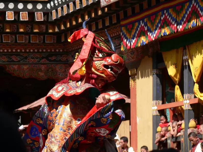A masked dancer in a brocade robe during the dance of the Lord of Death at Paro Tshechu