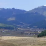 The wide floor of the Phobjikha valley, with forested hills on either side