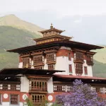 The central tower of Punakha Dzong, with jacaranda in flower below it
