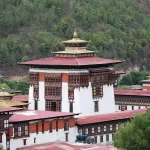 Tashichho Dzong in Thimphu, with its red roofs and white walls below a forested hill