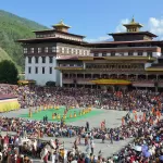 The festival ground beside Tashichho Dzong, crowded for Thimphu Tshechu, with dancers in the centre