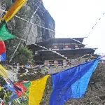 Tiger's Nest monastery seen through bright prayer flags from the path opposite