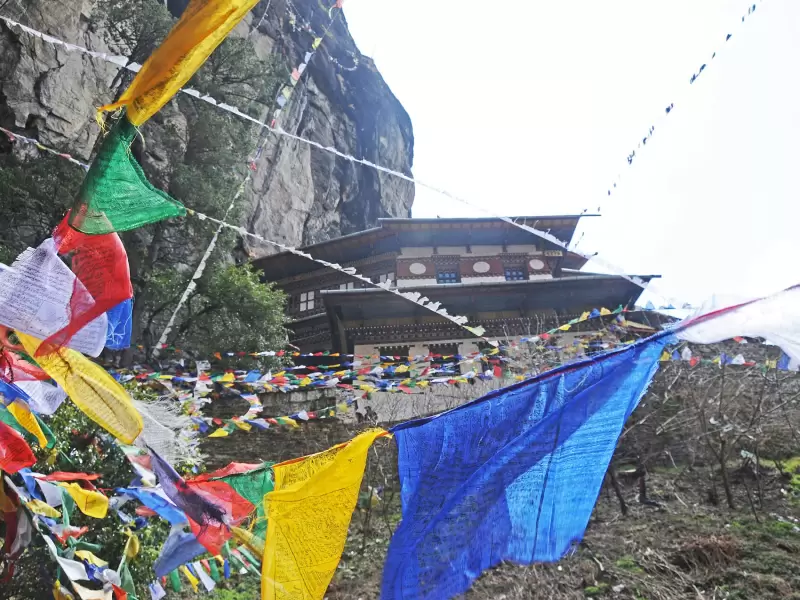 Tiger's Nest monastery seen through bright prayer flags from the path opposite