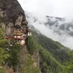Taktsang, the Tiger's Nest, on its cliff with cloud drifting through the forest below